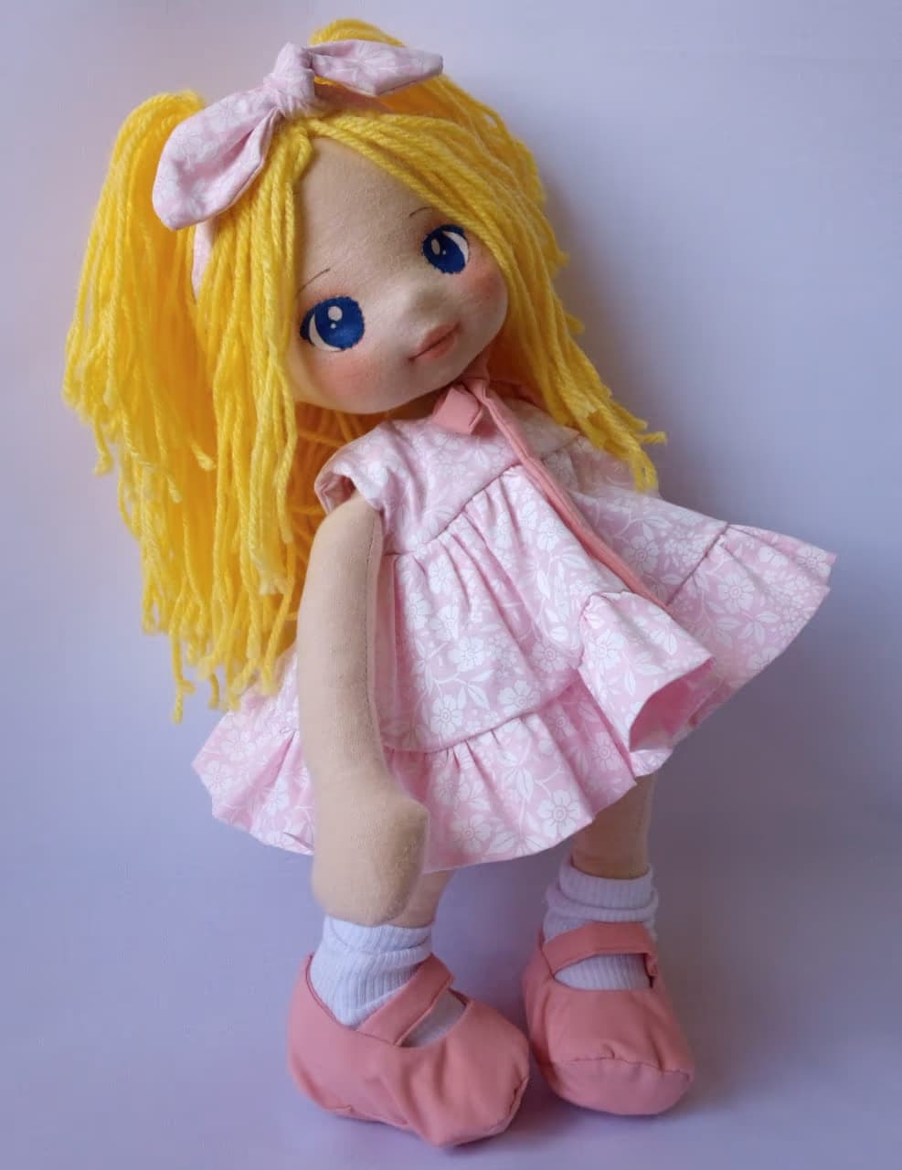 Boneca de pano loira com vestido rosa claro, sapatos rosa escuro e olhos azuis