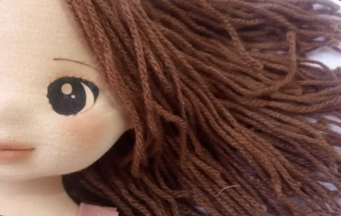 Selfe de rosto de boneca de pano morena com cabelo de fio de lã